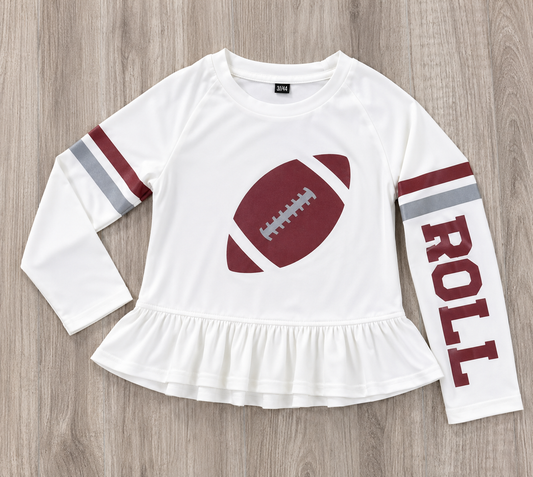 A white long-sleeve t-shirt with a ruffled hem, featuring a crimson football graphic on the chest, crimson and gray stripes on the sleeves, and the word 'ROLL' printed vertically on one sleeve, laid flat on a gray wood background. This is a SPF t-shirt for girls for gameday in Alabama.
