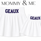 Two white pleated skirts shown on a white background, labeled 'MOMMY & ME' at the top. The larger skirt says 'GEAUX' in dark blue on the waistband, and the smaller skirt says 'GEAUX' as well. A Louisiana Gameday matching skirt set. 