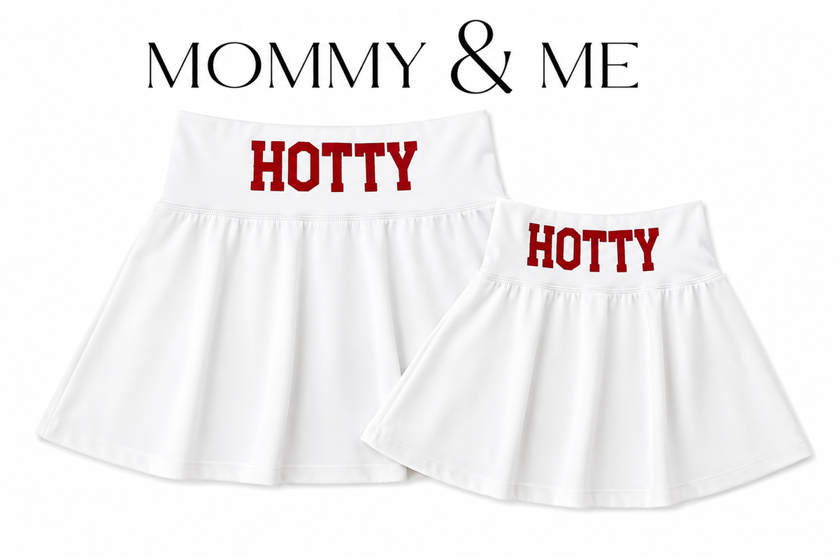 Two white tennis skirts  shown on a white background, one larger and one smaller, mommy and me both with the word 'HOTTY' printed in red across the waistband. Above the products, the text 'MOMMY & ME' appears in black. Made for Mississippi. 