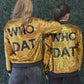 Two women standing with their backs to the camera, wearing matching gold sequined bomber jackets with 'WHO DAT' printed in black across the back, posed against a green textured wall. For New Orleans fans. 